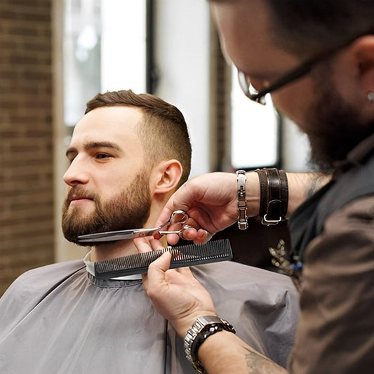 coiffeur taillant la barbe de son client avec le ciseaux précision