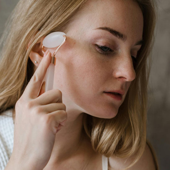 une femme se massant tranquillement le visage avec le gua sha